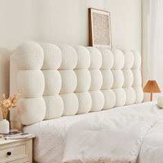 there is a white headboard made out of pillows on the bed with two nightstands next to it