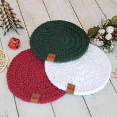 three crocheted round placemats sitting on top of a wooden floor next to christmas decorations