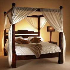 a four poster bed with white drapes and pillows