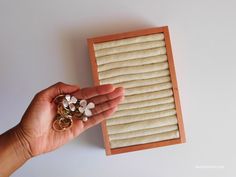 a person holding some rings in their hand next to a wooden box with beads on it