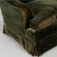 a green velvet couch sitting on top of a white floor