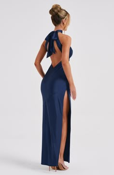 Here's to the nights you will remember because of the fits you won't forget. You will be unforgettable in Etta, our luxe maxi made from bias cut satin that skims beautifully over the body. The dress is completely backless with a high neck and an oversized tie neck detail. Elevate any look with Etta, platform heels and a sleek knot.   Colour: Navy.  Luxury bias cut satin.  High neckline.  Backless detail.  Skims over the figure.  Flares gently at the hem.  Maxi length.  Model is an XS and is wear Navy Blue Dresses Formal, Blue Maxi Dress, Homecoming Dresses Corset, Navy Blue Prom Dresses, Dresses Flowy, Midi Dress Wedding Guest, Long Sleeve Homecoming Dresses, Homecoming Dresses Long, Long Blue Dress