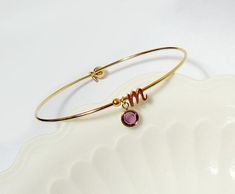 The following letters are out of stock:Silver cursive 'a'These are simple and beautiful! This listing is  Swarovski Birthstone initial Bangle.Choose the color of stone to represent your birthday, or your children's birthdays! These are great alone or all stacked together.A cute everyday bracelet with a tiny lowercase gold plated  charm and a gold plated self-closure bangle.Simple enough for everyday wear and looks great stacked and layered.Also makes great gifts for bridal parties, birthdays, gr Initial Bangle Bracelet, Personalised Bangle, Bracelet Initial, The Bangles, Everyday Bracelet, Bridal Parties, Letter Bracelet, Bracelet Dainty, Personalized Bridesmaid Gifts