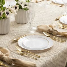 the table is set with white and gold plates, napkins, and silverware