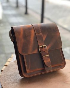 "The bag is crafted from high quality crazy horse leather that improves its appearance and solid construction over time. As you use it, natural patinas emerge and each bag has a unique look. You can safely use it with  your iPad, tablet, book, passport, phone. This leather messenger bag offers both style and functionality. It has a large main compartment and a large front compartment with a business card pocket. Adjustable leather strap provides a comfortable fit. The bag is fastened with magnetic buttons and has a fixed loop for hanging a key chain inside. The dimensions are as follows: Small: 17.5 cm x 18.5 cm x 6 cm (6.9\" x 7.3\" x 2.3\") in inches Big: 21cm x 21cm x 6cm (8.2\" x 8.2\" x 2.3\") in inches We offer customization options, making it the perfect gift. The bag will be ready Leather Saddle Bag With Waxed Finish Satchel, Leather Saddle Bag With Waxed Finish For Everyday Carry, Leather Saddle Bag With Waxed Finish, Oiled Leather Shoulder Bag With Waxed Finish, Waxed Oiled Leather Shoulder Bag, Everyday Shoulder Bag With Adjustable Strap In Oiled Leather, Rectangular Waxed Shoulder Bag For Everyday, Daily Use Oiled Leather Shoulder Bag With Adjustable Strap, Distressed Brown Satchel Bag With Leather Lining