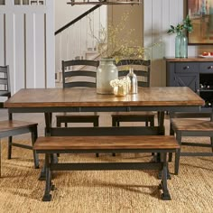 a dining room table with two benches and a vase on the table next to it