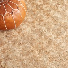 a brown ottoman sitting on top of a rug next to a small orange poufce