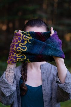 a woman covering her face with a scarf in front of her head and trees behind her