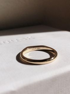 two gold wedding bands sitting on top of a white box