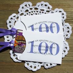 two white envelopes with purple ribbons on top of a doily that says happy birthday