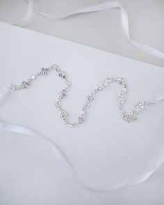 Dainty series of rhinestones attached in white satin ribbon gives a delicate and elegant touch to your hair do. Perfect for wedding, brides and bridesmaids, holiday party, casual wear, and any special occasions. DETAILS:COLOR: SILVERLENGTH: 0.5"WIDTH: 17"ASSEMBLED IN USAIMPORTED MATERIALS