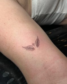 a woman's arm with a small tattoo of a bird on the left side