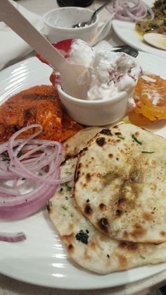 an assortment of food on a white plate with a knife and bowl in the background