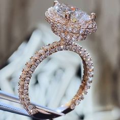 a diamond ring is being held up by a pair of tongs