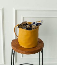 a yellow bucket sitting on top of a wooden table next to a white door and black metal chair