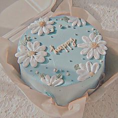 a blue cake with white flowers and the words happy written on it in frosting