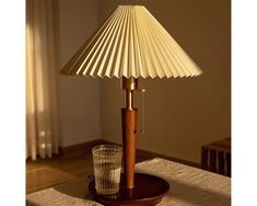 a lamp that is sitting on a table next to a glass and a drink in front of it