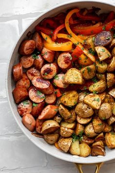 a pan filled with potatoes and peppers on top of a white countertop next to a wooden spatula