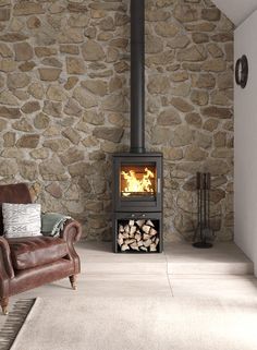 a living room with a couch, chair and fire place in the corner by a stone wall