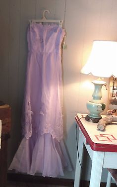 there is a dress hanging on the wall next to a table with a lamp in it