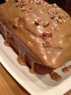 there is a cake with frosting and nuts on it sitting on a white plate