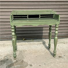 an old green desk is sitting on the sidewalk in front of a garage door,