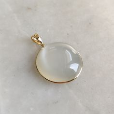 ITEM DESCRIPTION: >>The pendant is made from Solid 14K Yellow Gold. Gemstone used is absolutely natural and ethically sourced.  >>Natural White Moonstones cabochon cut and round shape with bezel setting are studded on it with utmost precision.  >>This is a minimalist design and is absolutely hassle-free and everyday jewelry.  ✓ Gem: White Moonstone ✓ Gem size: 25x25 mm round  ✓ Gem weight: 37.93 carats ✓ Gold purity: 14K (58.33% approx.) ✓ Gold weight: 0.81 grams  ✓ Gross weight: 8.40 grams The Gold purity is guaranteed and it comes with authentic 14K gold hallmark. Since these Pendants are handmade, they are Nickel/Lead FREE.  CUSTOMIZATION: --> You can choose your own gemstone as well. --> The same pendant can be made in thicker bezel as well. --> Kindly drop a message for the same. CUST Gold Polished Moonstone Jewelry, Gold Moonstone Jewelry With Polished Finish, White 14k Gold Jewelry With Round Stone, Modern Yellow Gold Moonstone Jewelry, White Polished Finish Round Pendant Jewelry, White Moon-shaped Gemstone Jewelry, Elegant Chalcedony Jewelry With Polished Finish, White Chalcedony Jewelry For Anniversary, White Oval Jewelry With Moon Charm