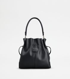 The iconic Tod's Di Bag style reinterpreted in an elegant bucket bag version, closed with a maxi drawstring. Crafted in soft full grain leather, with its distinctive Tod's logo stamped on the front, this versatile bag features tubular handle and adjustable shoulder strap, both removable. Completed with an internal pouch, it accompanies your everyday outfit with class and femininity. Timeless Bucket Bag With Leather Lining, Classic Calf Leather Bucket Bag With Detachable Handle, Soft Calf Leather Bucket Bag, Classic Calf Leather Bucket Bag, Timeless Soft Leather Bucket Bag, Calf Leather Bag With Removable Pouch In Bucket Shape, Calf Leather Bucket Bag With Handle Drop For Travel, Classic Calf Leather Bucket Bag For Shopping, Luxury Calf Leather Bucket Hobo Bag