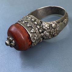 Antique ~ Very well Handmade ~ old Yemeni silver ring ~ Featuring a large central amber or amber resin set on an closed back bezel setting with wire and beaded border ~ Unsigned but acid tested for atleast 800 silver . Dates first half or 20th century Measurements : Ring can fit size 8 - 8 1/2 . Front is 1/2 inches in max diameter x 5/8inches in height Weighs 9 grams on my weighing scale . Condition : Good old condition ,with heavy age patina to silver and central bead ~ No cracks /chips to cora Unique Brown Jewelry For Ceremonial Occasions, Unique Carved Ring Jewelry, Bohemian Carved Amber Jewelry, Traditional Amber Jewelry With Carved Details, Vintage Carved Amber Jewelry, Handmade Bohemian Amber Rings, Vintage Amber Carved Jewelry, Bohemian Carved Ring Jewelry, Bohemian Amber Sterling Silver Rings