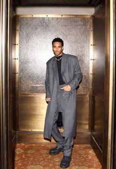 a man standing in an elevator wearing a suit and tie