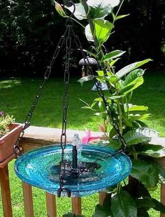 a bird bath sitting on top of a wooden fence next to a potted plant