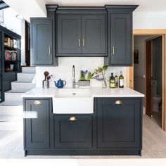 a kitchen with dark gray cabinets and white counter tops is seen in this image from the doorway