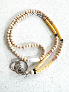 a wooden beaded necklace with two keychains attached to it on a white surface