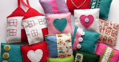 a pile of colorful handmade bags with hearts and houses on them sitting next to each other