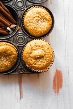 three muffins in a cupcake tin with cinnamon sticks