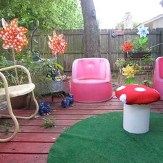 the backyard has been decorated with pink and white furniture, including two mushroom shaped chairs