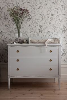 a baby crib with flowers on it in front of a wallpapered wall