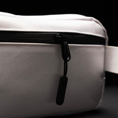 a close up of a white and black bag on a dark surface with the zipper open