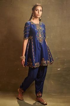 Royal blue kalidar top in dupion silk base featuring multi colored thread embroidery and embellished with cutdana, sequins and zardozi. Paired with dupion silk dhoti pant.
Component: 2
Embroidered
Neckline: Round
Sleeve Length: Elbow
Fabric: Dupion Silk
Color: Blue
Back keyhole button closure
Cutwork kurta hem - Aza Fashions Long Blouse Designs, Desi Fashion Casual, Kurti Designs Party Wear, Suits Design, Dupion Silk, Dress Indian Style, Fancy Party, Organza Dupatta, Pakistani Dress Design