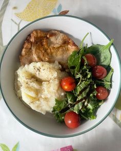 a white bowl filled with meat, mashed potatoes and veggies on top of a table