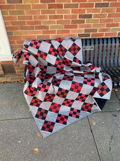 a black and red checkered blanket sitting on the ground next to a metal bench