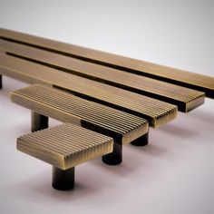 three wooden benches sitting next to each other on top of a white surface with black legs