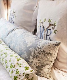 the pillows on the bed are decorated with green and white floral designs, along with monogrammed letters