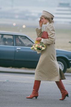 a woman walking down the street talking on her cell phone while holding flowers in her hand