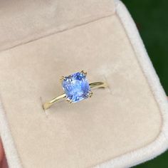 a person holding a ring with a blue stone in it's center and gold band