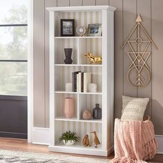 a white bookcase sitting next to a window in a living room with striped walls