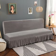 a gray couch sitting on top of a wooden floor next to a lamp and pictures