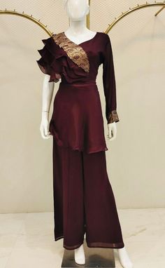 A sophisticated Indo-Western palazzo set in a chocolate brown hue, featuring both a top and bottom. The plain top is gracefully designed with a single full-length sleeve, while the opposite sleeve is tastefully adorned with delicate ruffles. The neckline is embellished with sequin embroidery on one side, perfectly complementing the eloquent elbow sleeve. The set is completed with plain palazzo pants, ensuring comfort throughout the day. Note: Colors may slightly vary due to photographic lighting Elegant Pant Set For Wedding And Festive Occasions, Elegant Wedding Pant Set, Elegant Festive Wedding Pant Set, Wedding Festive Elegant Pant Set, Silk Long Sleeve Formal Pant Set, Silk Long Sleeve Pant Set For Formal Occasions, Formal Silk Fitted Pant Set, Formal Fitted Silk Pant Set, Elegant Fitted Silk Pant Set