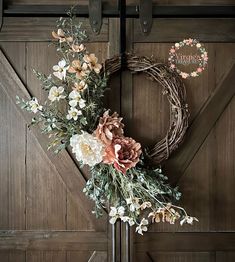 a wreath with flowers hanging on the side of a barn door