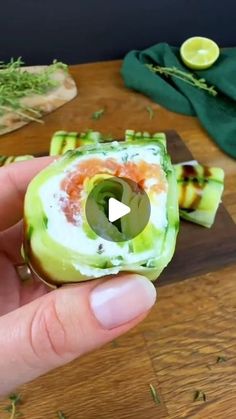 someone is holding an appetizer in their hand on a wooden table with other food items